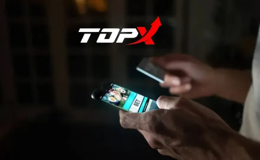 Mãos segurando um celular com a marca TopX ao fundo